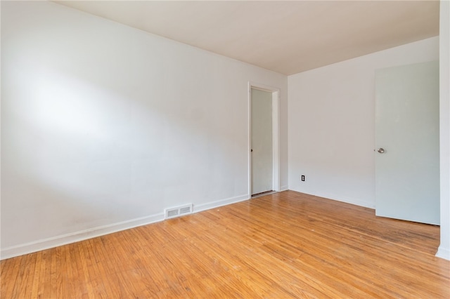 spare room featuring light wood finished floors, baseboards, and visible vents