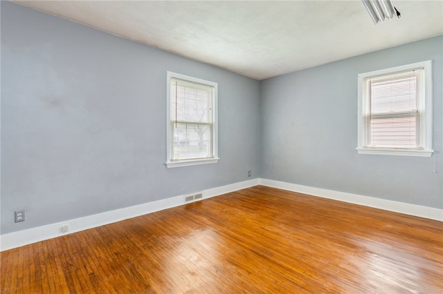 spare room with visible vents, wood finished floors, and baseboards