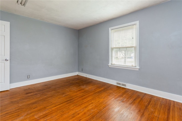 unfurnished room featuring visible vents, wood finished floors, and baseboards