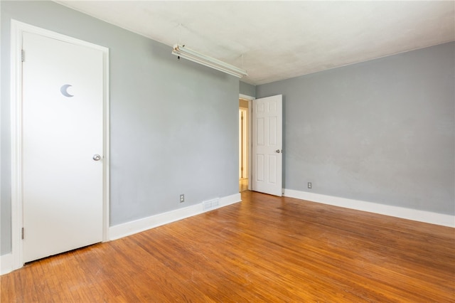 spare room with visible vents, wood finished floors, and baseboards