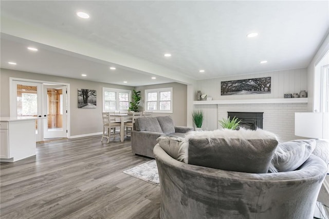 living area featuring baseboards, a brick fireplace, recessed lighting, and wood finished floors