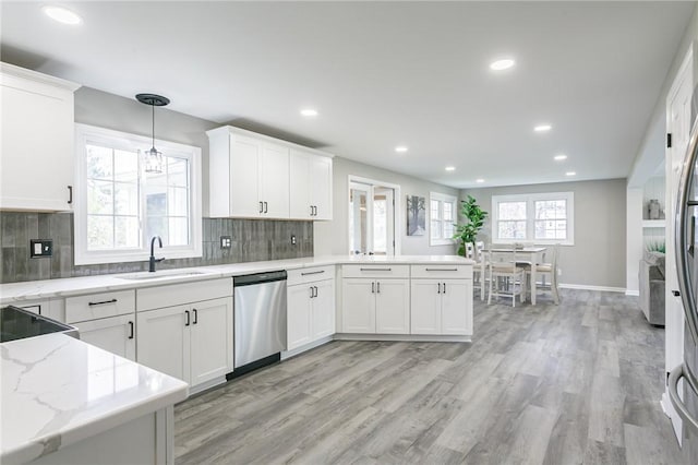 kitchen with light wood-style flooring, recessed lighting, stainless steel dishwasher, a sink, and a peninsula