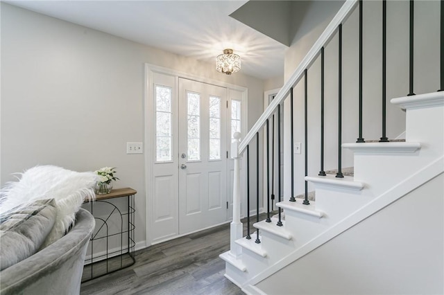 entrance foyer featuring baseboards, a notable chandelier, stairway, and wood finished floors