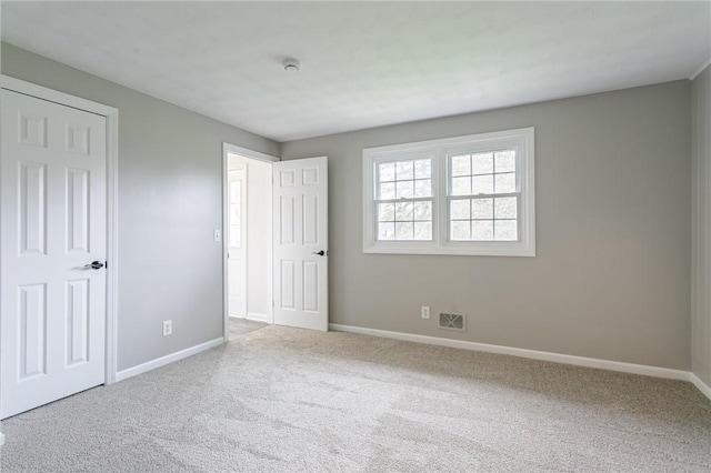 unfurnished bedroom featuring baseboards, visible vents, and carpet