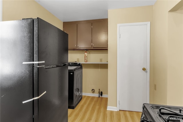 kitchen with black appliances, washer / dryer, light wood finished floors, and light countertops