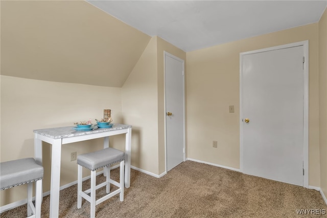 carpeted dining area featuring vaulted ceiling and baseboards