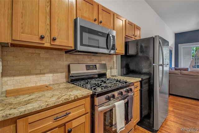 58 Park St, Buffalo, NY 14201 - kitchen with stainless steel appliances, light wood-style flooring, decorative backsplash, light stone countertops, and open floor plan