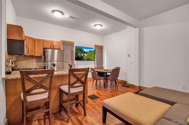58 Park St, Buffalo, NY 14201 - kitchen featuring appliances with stainless steel finishes, light wood-style floors, brown cabinetry, and a peninsula