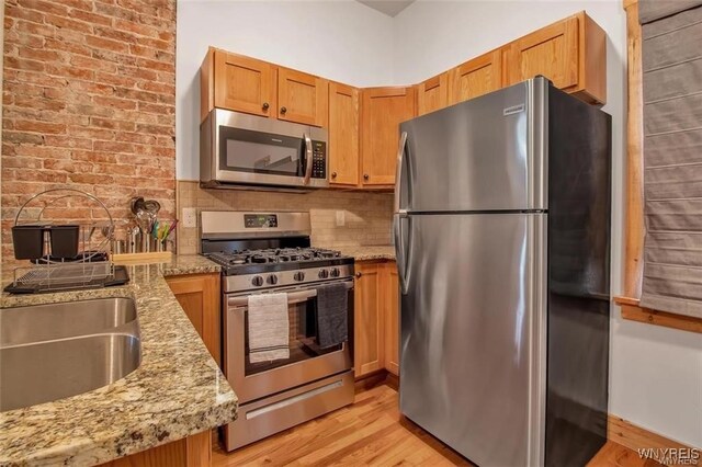 58 Park St, Buffalo, NY 14201 - kitchen with appliances with stainless steel finishes, light stone counters, light wood-style floors, and tasteful backsplash