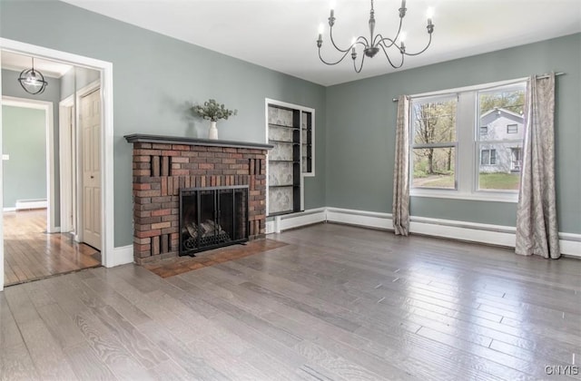83 Salisbury St, Sandy Creek, NY 13083 - unfurnished living room featuring wood finished floors, a brick fireplace, a notable chandelier, baseboards, and a baseboard heating unit