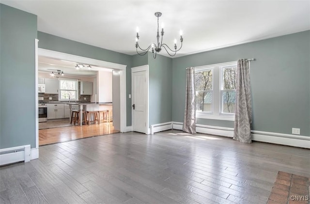 83 Salisbury St, Sandy Creek, NY 13083 - unfurnished dining area featuring an inviting chandelier, wood finished floors, a sink, baseboards, and baseboard heating