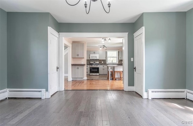 83 Salisbury St, Sandy Creek, NY 13083 - unfurnished living room featuring wood finished floors, a sink, baseboards, a chandelier, and a baseboard radiator
