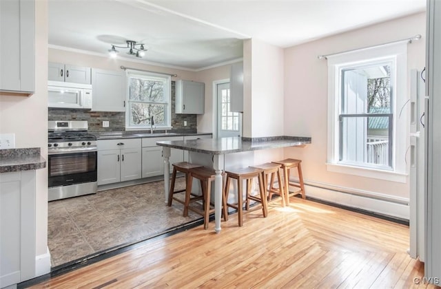 83 Salisbury St, Sandy Creek, NY 13083 - kitchen featuring stainless steel gas range, a sink, dark countertops, baseboard heating, and white microwave