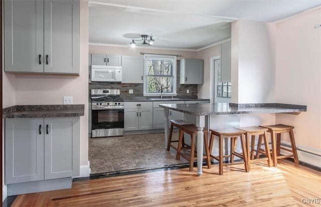 83 Salisbury St, Sandy Creek, NY 13083 - kitchen featuring white microwave, stainless steel gas range oven, a kitchen bar, and gray cabinets