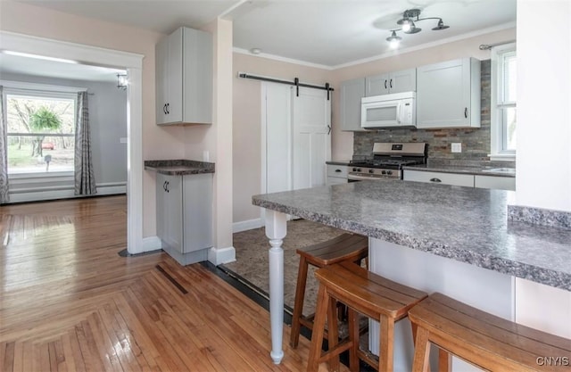 83 Salisbury St, Sandy Creek, NY 13083 - kitchen with a kitchen bar, a barn door, white microwave, decorative backsplash, and gas stove