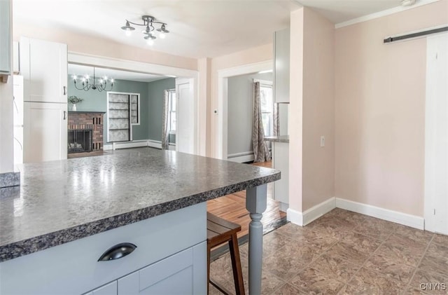 83 Salisbury St, Sandy Creek, NY 13083 - kitchen featuring a breakfast bar area, a fireplace, baseboard heating, a notable chandelier, and dark countertops