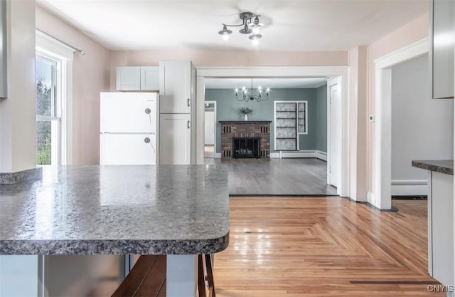 83 Salisbury St, Sandy Creek, NY 13083 - kitchen featuring an inviting chandelier, freestanding refrigerator, dark countertops, a fireplace, and white cabinets