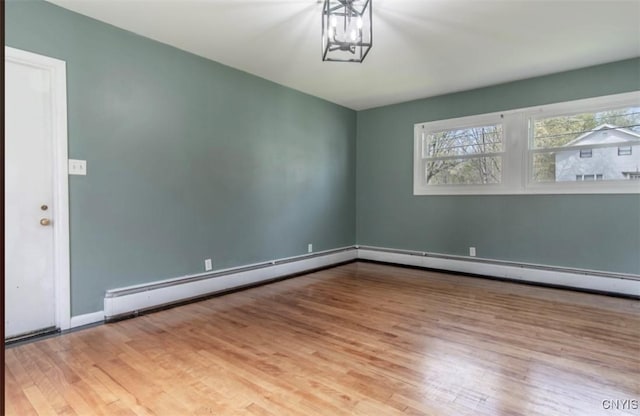 83 Salisbury St, Sandy Creek, NY 13083 - empty room with baseboards, a notable chandelier, a baseboard radiator, and wood finished floors