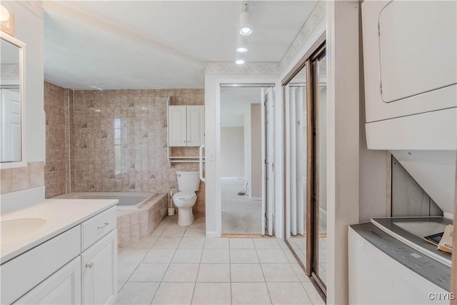 8733 State Route 289, Ellisburg, NY 13605 - bathroom featuring toilet, a relaxing tiled tub, stacked washer / drying machine, tile patterned floors, and vanity