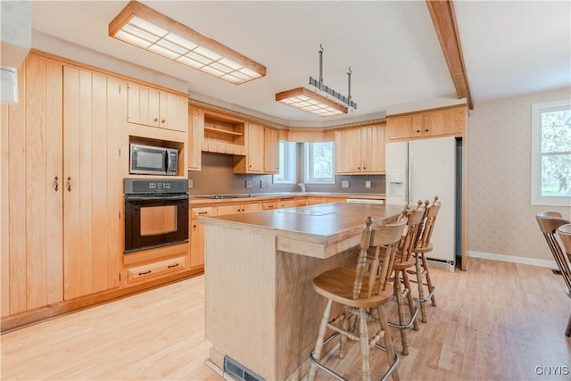 8733 State Route 289, Ellisburg, NY 13605 - kitchen with stainless steel microwave, black oven, light wood finished floors, light brown cabinetry, and white refrigerator with ice dispenser