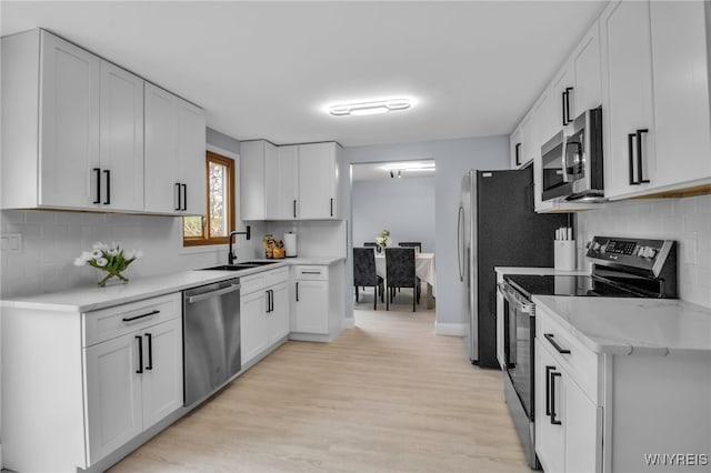 kitchen featuring a sink, light wood finished floors, stainless steel appliances, and light countertops