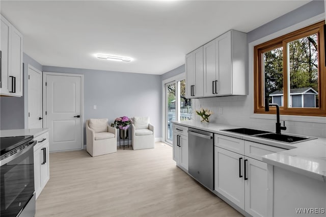 kitchen with electric range oven, light wood-style flooring, a sink, and stainless steel dishwasher