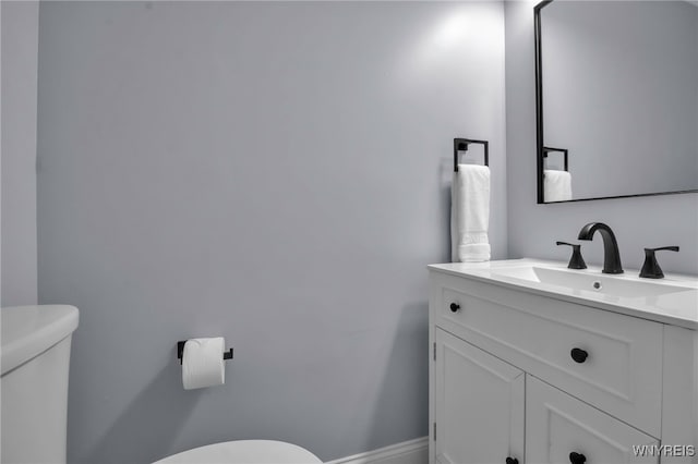 bathroom with toilet, baseboards, and vanity