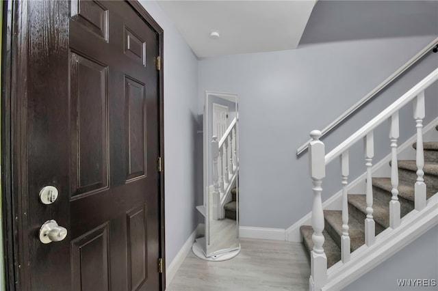 entryway featuring stairs, baseboards, and wood finished floors