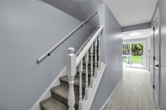 staircase featuring baseboards and wood finished floors