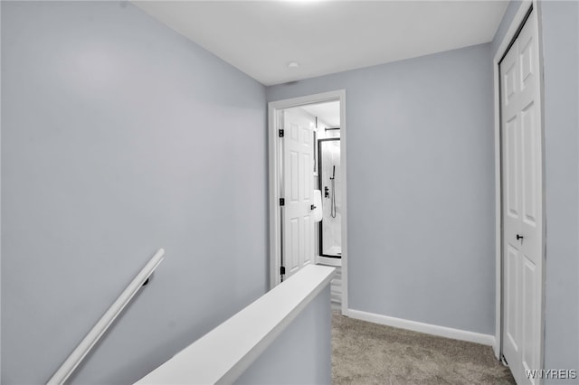 corridor with light carpet, an upstairs landing, and baseboards