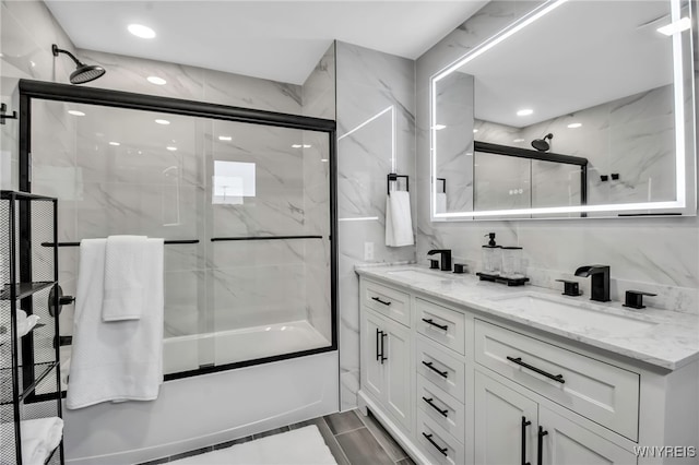 full bath featuring combined bath / shower with glass door, a sink, and double vanity