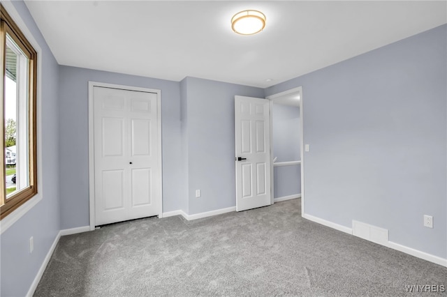 unfurnished bedroom featuring carpet, visible vents, and multiple windows