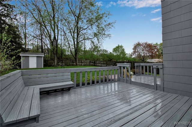 wooden terrace with an outdoor structure, a fenced backyard, and a storage unit