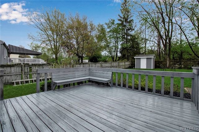 wooden deck with a fenced backyard, a storage unit, an outbuilding, and a lawn