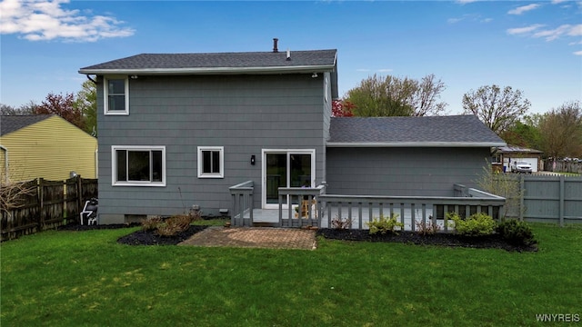 back of house with a shingled roof, a yard, and a fenced backyard