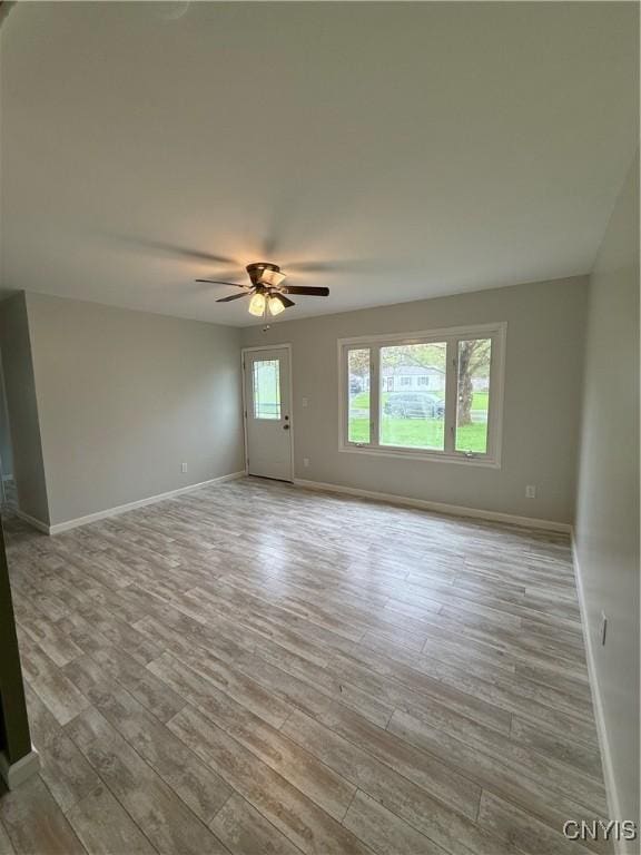empty room featuring baseboards, a ceiling fan, and wood finished floors