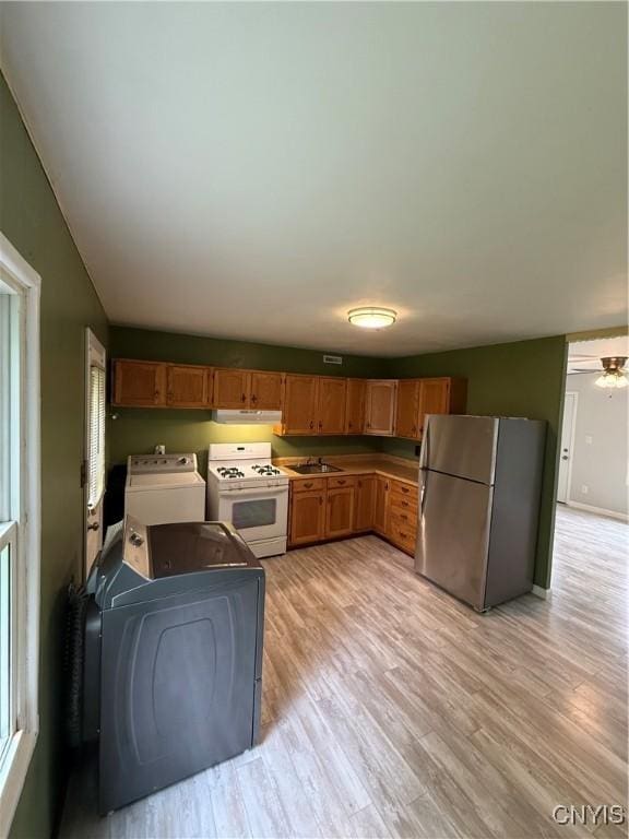 kitchen with washing machine and dryer, light wood-style flooring, freestanding refrigerator, white gas range, and under cabinet range hood
