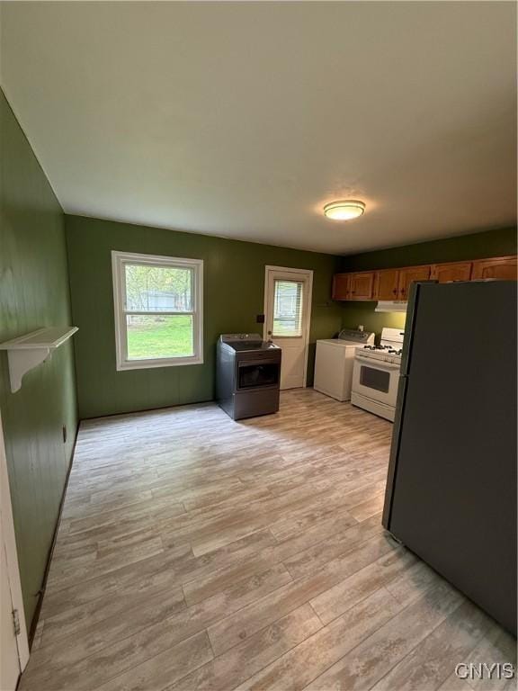 kitchen featuring washer / dryer, freestanding refrigerator, a wealth of natural light, stove, and white range with gas stovetop