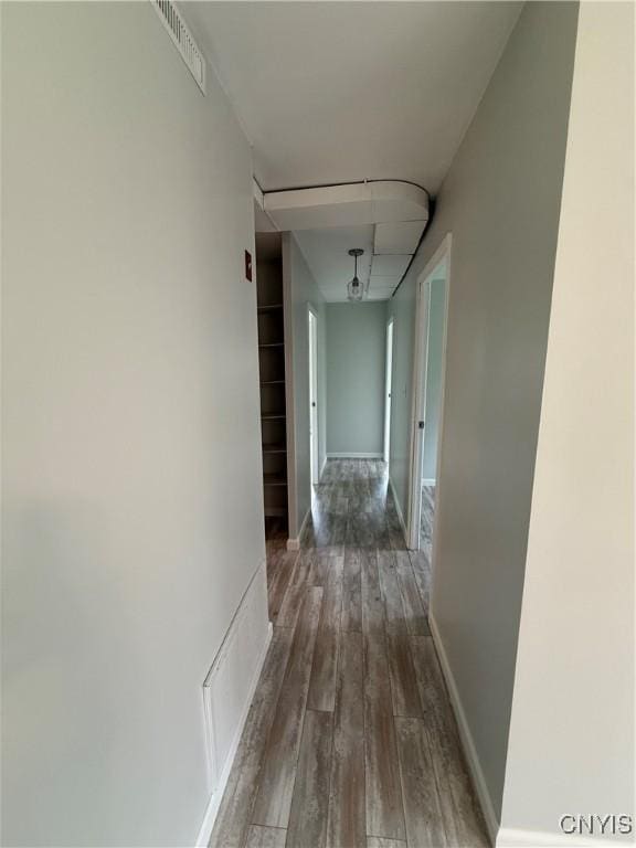 hall featuring wood-type flooring, baseboards, and visible vents