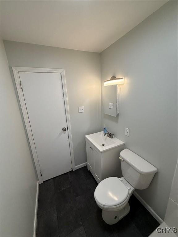 half bath featuring toilet, baseboards, and vanity