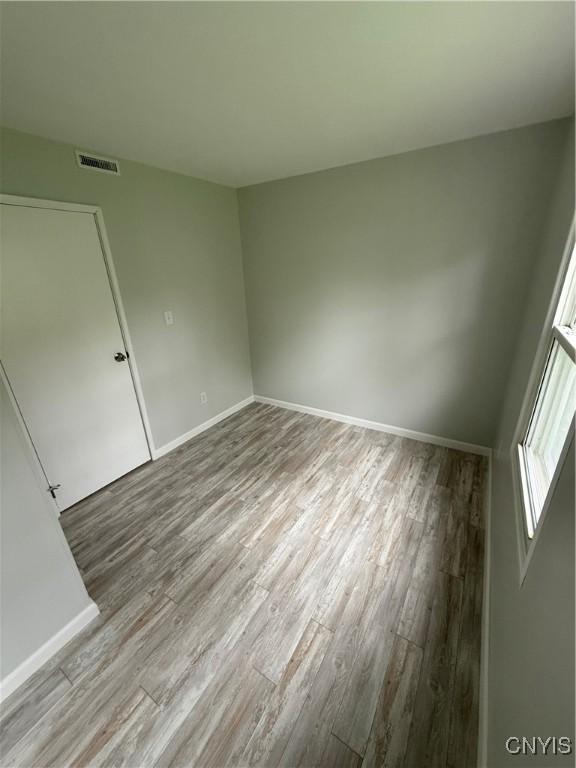 empty room featuring baseboards, visible vents, and wood finished floors