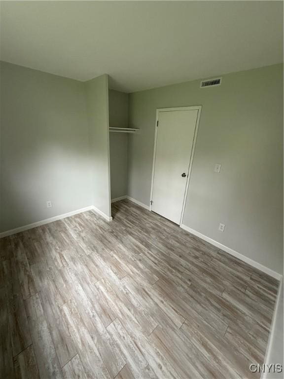 unfurnished bedroom with a closet, visible vents, wood finished floors, and baseboards