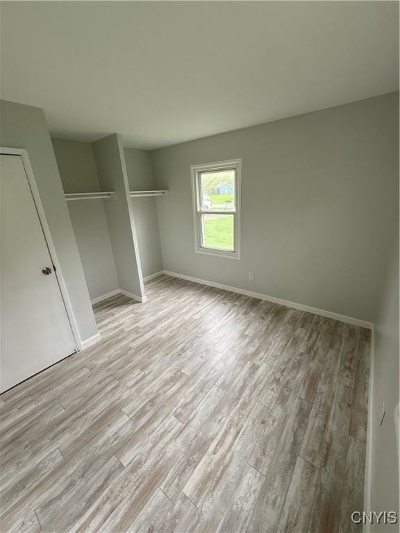 unfurnished bedroom with a closet, wood finished floors, and baseboards