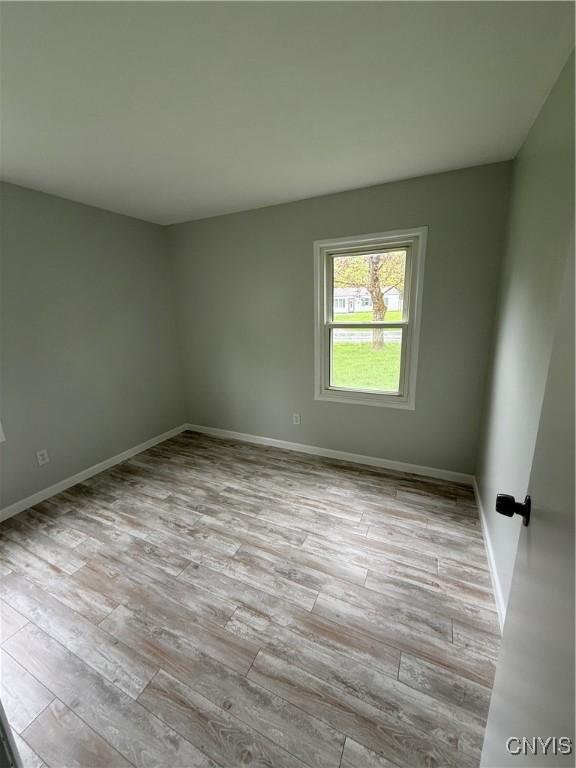 spare room with baseboards and wood finished floors
