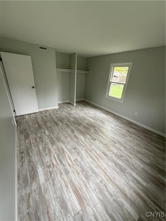 unfurnished bedroom featuring a closet, visible vents, wood finished floors, and baseboards