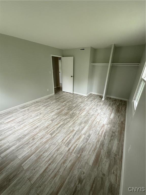 unfurnished bedroom with baseboards, visible vents, and wood finished floors