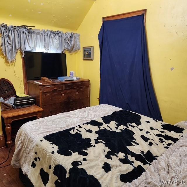 bedroom with vaulted ceiling and wood finished floors