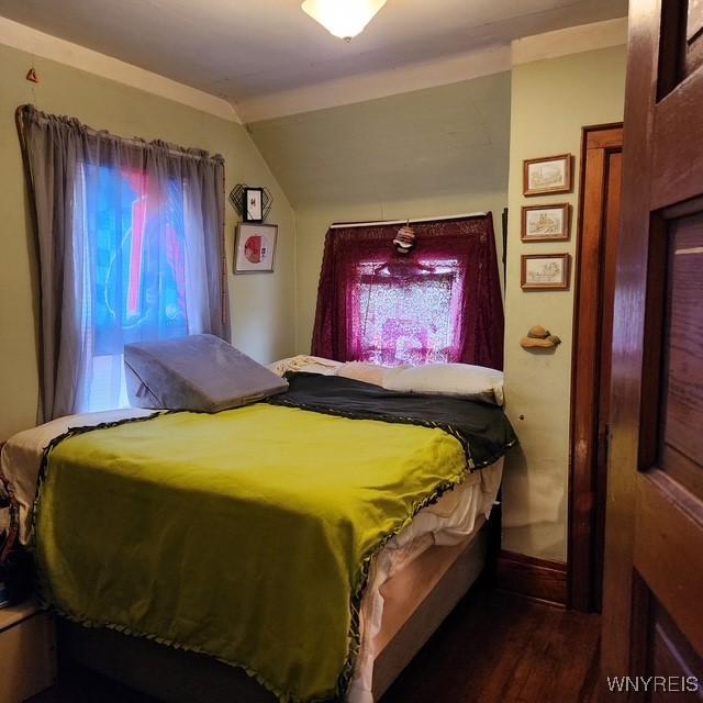 bedroom with lofted ceiling, baseboards, and wood finished floors