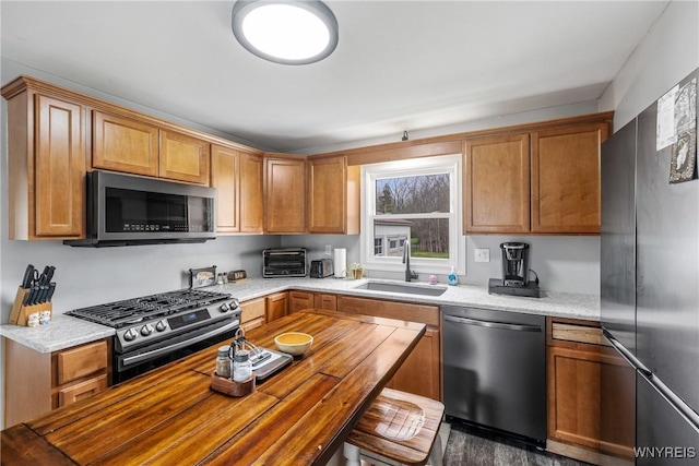 kitchen featuring appliances with stainless steel finishes, a toaster, brown cabinets, and a sink