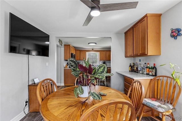 dining room with a bar, baseboards, and ceiling fan
